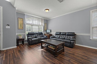 Living area with crown molding, wood finished flo