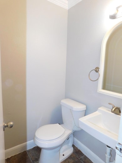 Half bathroom featuring toilet, crown molding, ba