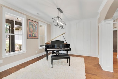 Living area with crown molding, wood finished floors, and a decorative wall