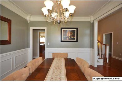 Formal dining room with hardwood floor, chair rail, wainscot and crown molding opens from the entry foyer.