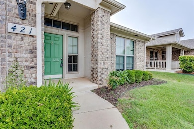 Doorway to property featuring a porch, brick siding, a lawn, and a shingled roof