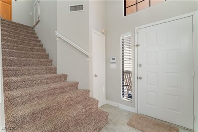 Foyer with light tile patterned flooring and stairs