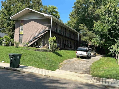 View of front facade with stairway, a front lawn, driveway, and brick siding