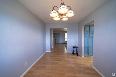 Corridor with a chandelier and light wood-type flooring