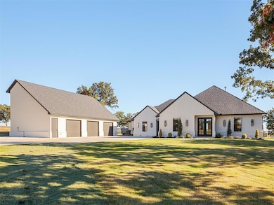 View of front of home with french doors, roof with shingles, an outdoor structure, a front lawn, and a garage
