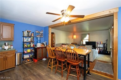 Dining area with dark wood-style flooring, a ceiling fan, and arched walkways