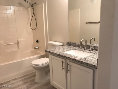 Bathroom with bathing tub / shower combination, vanity, and light wood-type flooring