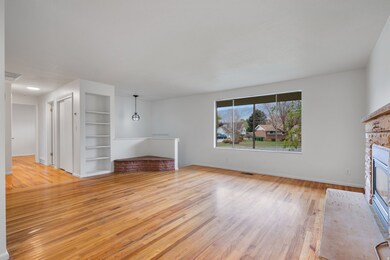 Unfurnished living room featuring light wood-style floors, a brick fireplace, and built in shelves