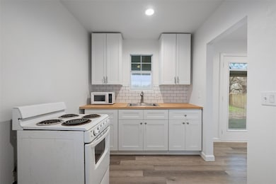 Kitchen featuring white appliances, butcher block counters, tasteful backsplash, and healthy amount of natural light