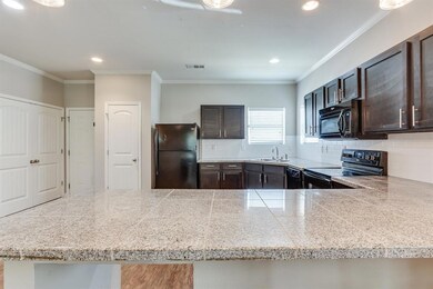 Kitchen featuring black appliances, tile counters, dark brown cabinets, ornamental molding, and tasteful backsplash