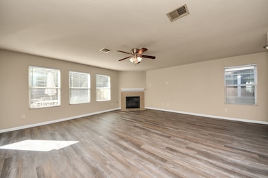 Generous open living room with vinyl flooring providing an excellent space for gatherings featuring a ceiling fan and fireplace.