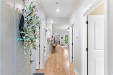 Corridor with crown molding, light wood-style floo