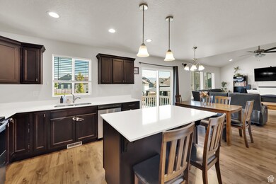 Kitchen featuring a kitchen bar, open floor plan, recessed lighting, light wood-style flooring, and dark brown cabinetry
