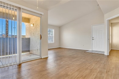 Empty room with lofted ceiling and light wood finished floors