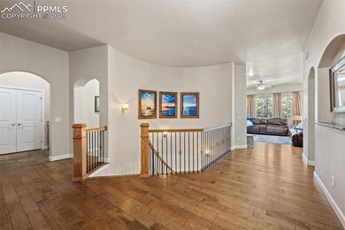 Hall with wood-type flooring, an upstairs landing, and arched walkways