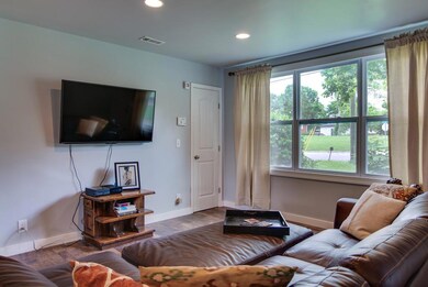 Recessed lighting, hardwood floors, and a large window for bright light make this living room very cozy.  