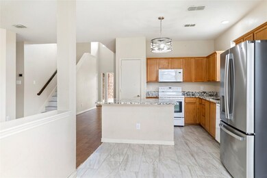 Kitchen with white appliances, light stone countertops, a kitchen island, hanging light fixtures, and brown cabinetry