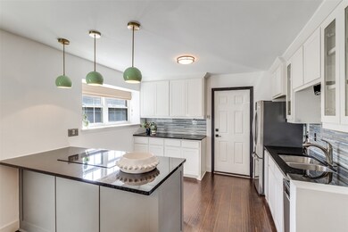 Kitchen with a peninsula, glass insert cabinets, hanging light fixtures, white cabinets, and freestanding refrigerator