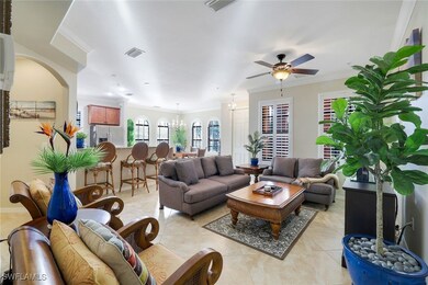 Tiled living room featuring ceiling fan with notable chandelier and ornamental molding