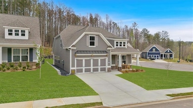 Craftsman-style home featuring a front lawn, a shingled roof, a garage, and driveway