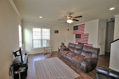 Living room featuring crown molding, ceiling fan,