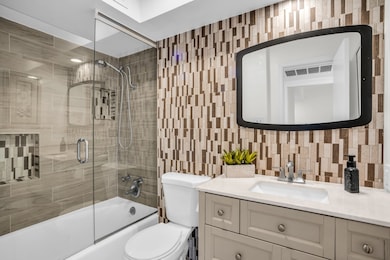 Full bathroom featuring combined bath / shower with glass door, vanity, backsplash, and tile walls