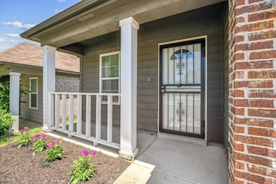 Doorway to property featuring covered porch and brick siding