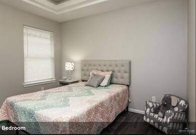 Bedroom with dark wood finished floors and baseboards