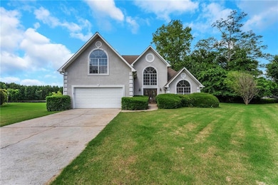 Traditional home with an attached garage, a front yard, driveway, and stucco siding