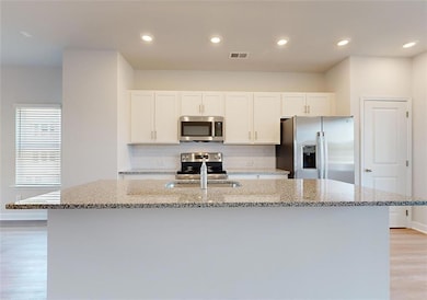 Kitchen with light stone counters, white cabinetry