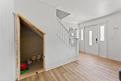 Entryway featuring wood finished floors, ornamental molding, and stairs