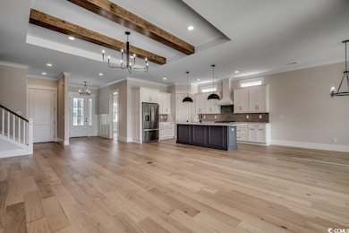 Kitchen with a chandelier, open floor plan, stainless steel fridge, custom exhaust hood, and recessed lighting