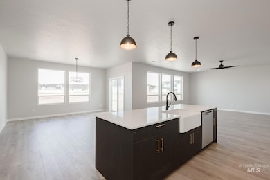 Kitchen featuring open floor plan, decorative light fixtures, ceiling fan, light wood-style flooring, and a textured ceiling