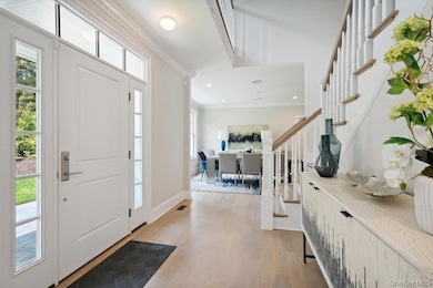 Entryway featuring crown molding, light wood-style flooring, stairway, and recessed lighting
