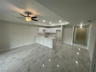 Kitchen with a peninsula, a sink, baseboards, a tr