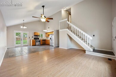 Unfurnished living room with stairway, baseboards, a chandelier, ceiling fan, and high vaulted ceiling