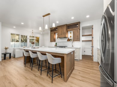 Kitchen featuring brown cabinets, freestanding refrigerator, a spacious island, open shelves, and recessed lighting