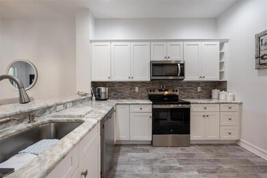 Kitchen with tasteful backsplash, white cabinetry,