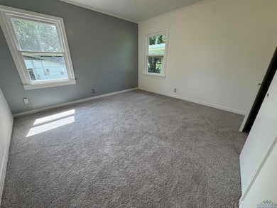 Spare room featuring carpet floors and baseboards
