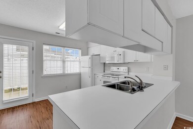 Kitchen featuring visible vents, white appliances, light countertops, and a sink