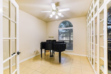 Living area featuring french doors, light tile patterned floors, and a ceiling fan