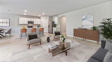 Living area featuring baseboards, light wood-style flooring, arched walkways, and recessed lighting