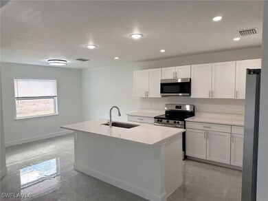 Kitchen with sink, white cabinets, a kitchen islan