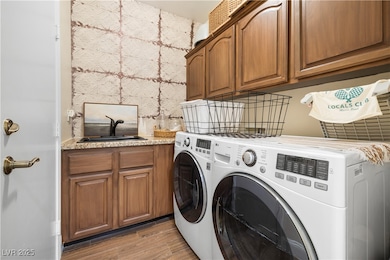 Clothes washing area featuring cabinet space, wash