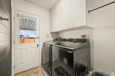 Laundry area featuring independent washer and dryer, cabinet space, and light tile patterned floors