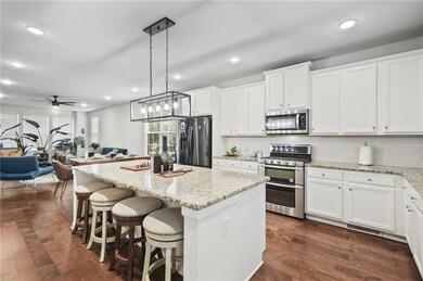 Kitchen featuring appliances with stainless steel finishes, recessed lighting, a kitchen island, dark wood finished floors, and white cabinets