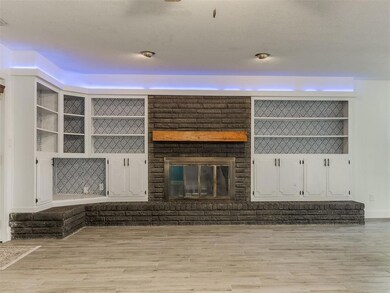 Unfurnished living room featuring light wood-type flooring, a brick fireplace, and a textured ceiling