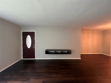 Front door from livingroom featuring dark wood-style flooring and baseboards