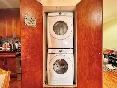 Laundry area featuring light wood-type flooring, sink, and stacked washer and clothes dryer