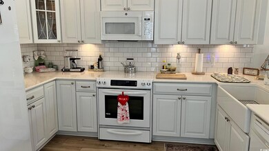 Kitchen with white cabinetry, dark hardwood / wood